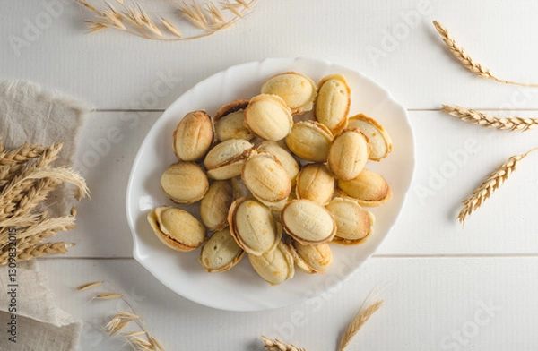 Fototapeta Delicious cookies in the shape of a nut filled with boiled condensed milk on a white wooden background, flat lay