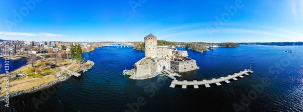 Fototapeta Beautiful aerial view of Olavinlinna, Olofsborg ancient fortress, the 15th-century medieval three - tower castle located in Savonlinna city on a sunny summer day, Finland. Shooting from a quadcopter.