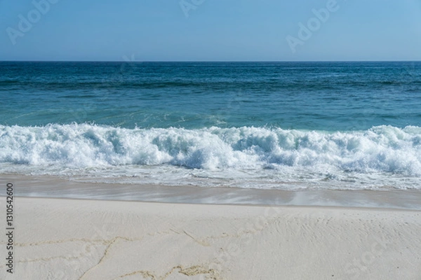 Fototapeta Small sized waves of Atlantic Ocean blue waters breaking on Praia Seca beach white sands shoreline under hot summer afternoon clear blue sky in Praia Seca district, Araruama, Rio de Janeiro - Brazil.