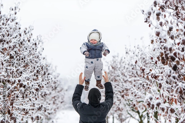 Obraz Happy father throws up her young son in winter day