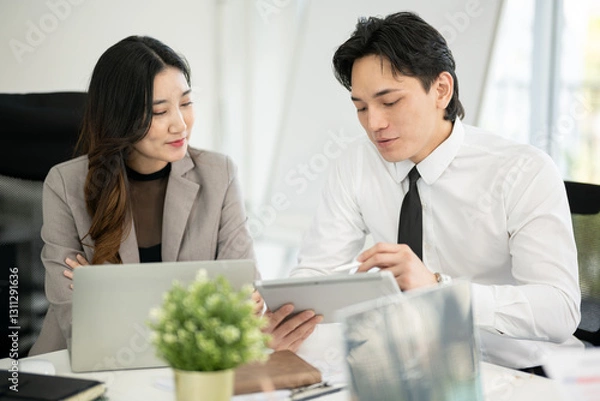 Fototapeta A male employee is presenting a business plan to a female executive in a conference room.