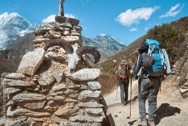 Fototapeta Group hikers with backpacks in mountains pass by an identifying ancient stupa made of flat stones on popular trail around Annapurna, Nepal.