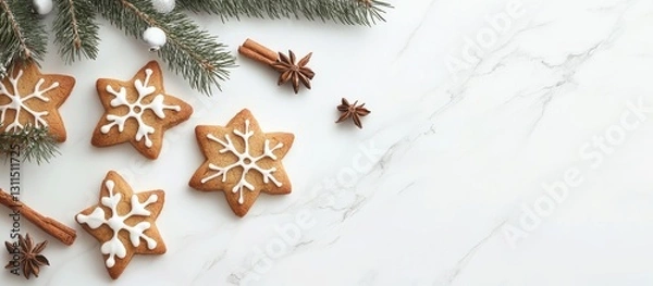 Fototapeta Decorative star-shaped Christmas cookies with icing surrounded by fir tree twigs and cinnamon sticks on a white marble table top viewed from above
