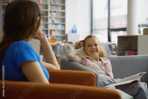 Fototapeta Woman and little girl child taking discussing book for reading