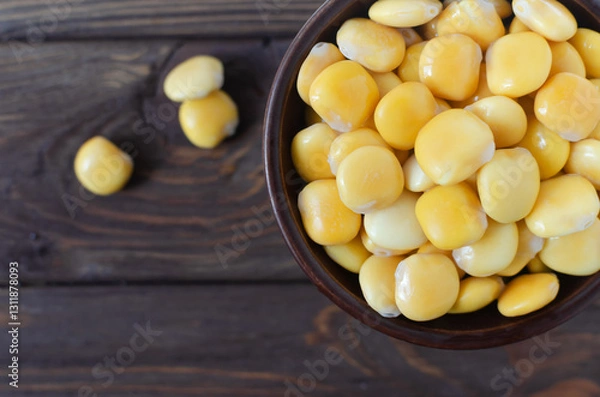 Fototapeta Lupin beans in a brown bowl on a wooden table. Italian food. Type of legumes. Healthy food concept. Horizontal orientation. Selective focus. Copy space. Top view