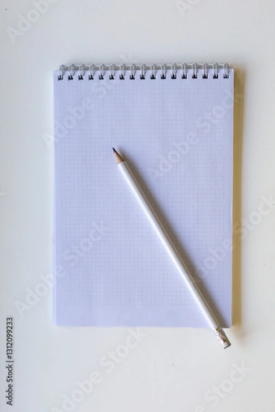 Obraz White pencil on spiral notepad with graph paper. 