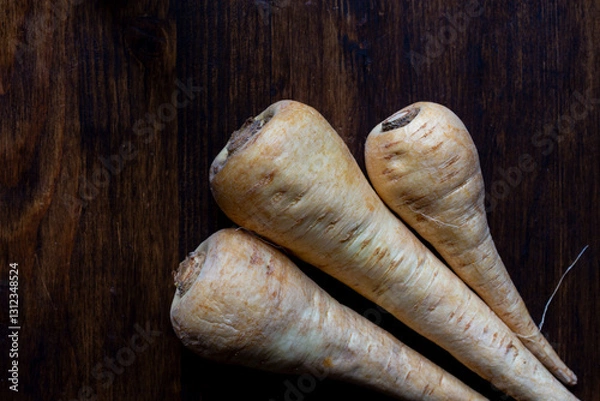 Fototapeta Aerial view of three parsnips on a wooden table, horizontal with copy space