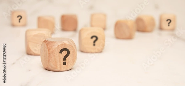 Fototapeta wooden blocks with question marks on a marble surface, symbolizing uncertainty and curiosity