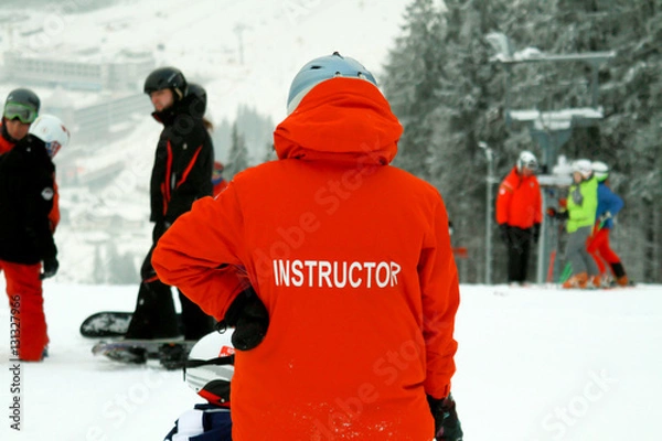 Fototapeta Snowboard instructor. Teaches snowboarding beginner. Rookie crashes but continues to learn.