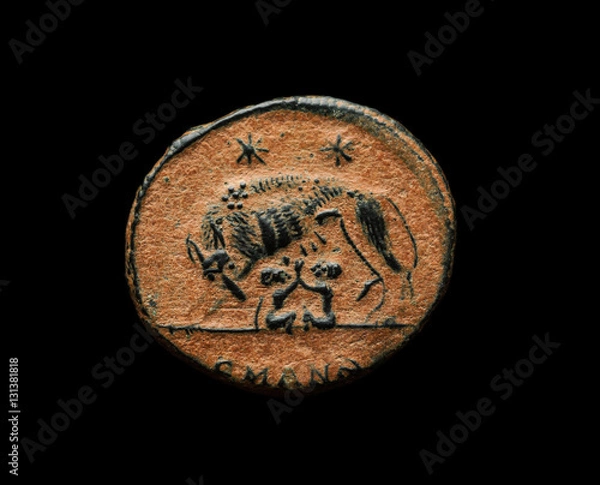 Fototapeta Ancient roman commemorative coin with image of Romulus, Remus and wolf isolated on black