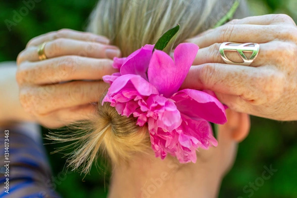 Fototapeta Blond woman fixing a flower in her bun.