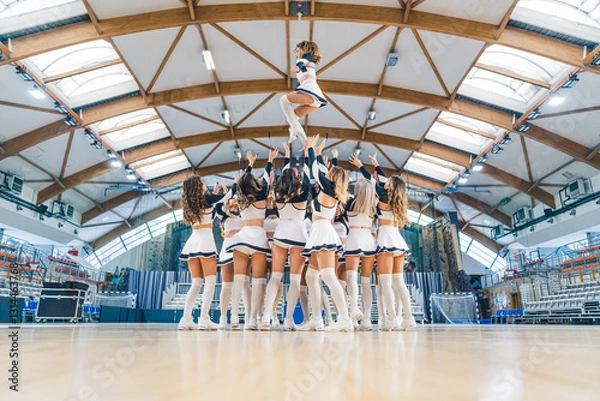 Fototapeta Cheerleaders Performing Dance Routine in Modern Sports Arena with Enthusiastic Spirit. High quality photo
