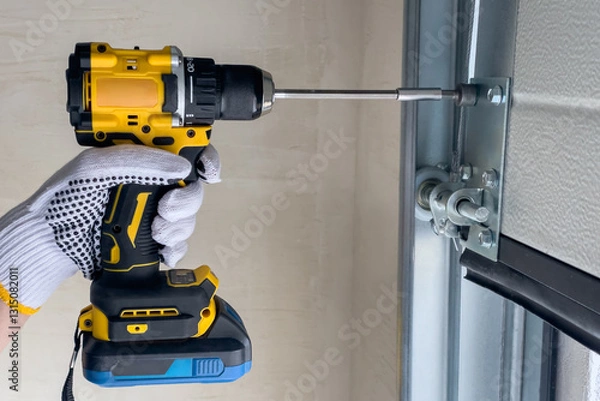 Obraz A craftsman assembles sectional doors using a screwdriver.