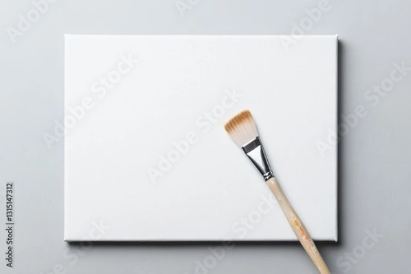 Fototapeta close-up of artist brush delicately poised above blank canvas with abundant copy space surrounding scene capturing