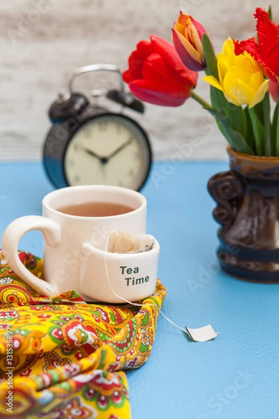 Obraz tea, tulips and alarm clock on a table, selective focus