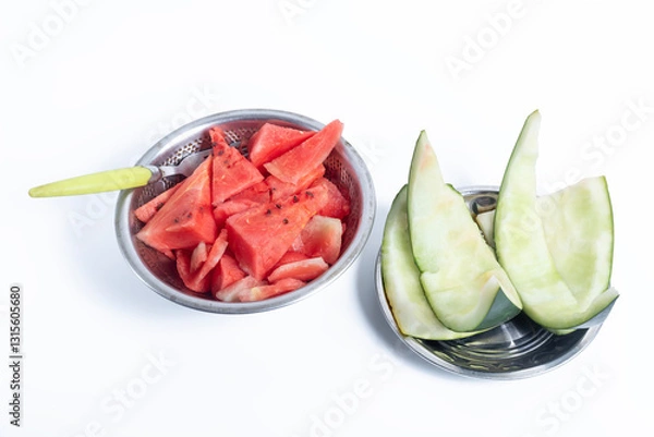 Fototapeta Closeup of watermelon with a spoon in bowls on a white background and watermelon rinds on a plate next to it.