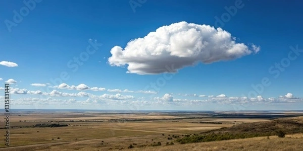 Fototapeta A lone white cloud floats serenely across the clear blue sky against a backdrop of endless plains and vast open spaces, floating, white cloud