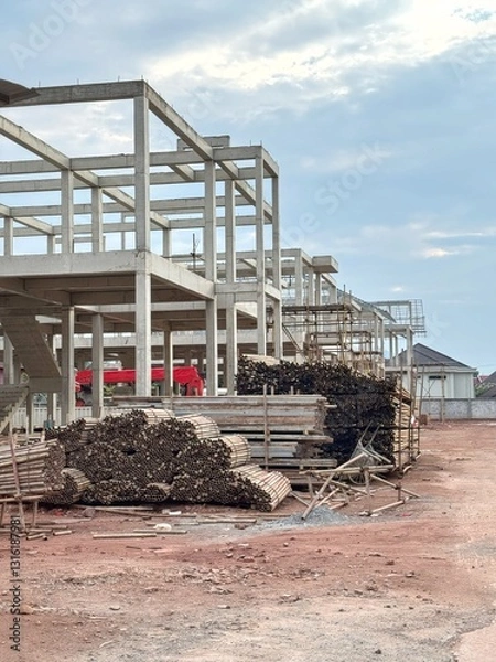 Obraz Reinforced steel and concrete building under construction, lumber pilling up