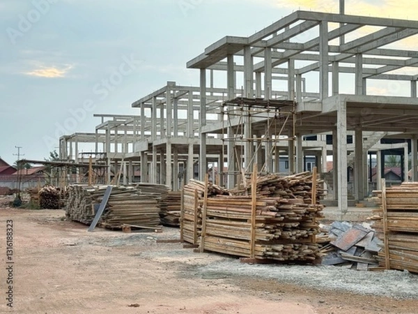 Obraz Reinforced steel and concrete building under construction, lumber pilling up.