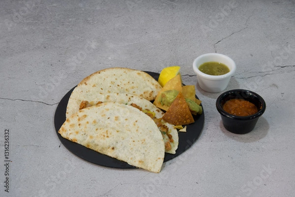 Obraz A plate of three tacos with a side of chips and a small cup of salsa