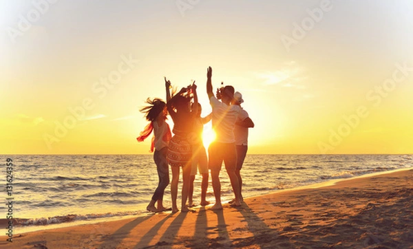 Fototapeta grupa szczęśliwych młodych ludzi tańczących na plaży na piękny letni zachód słońca