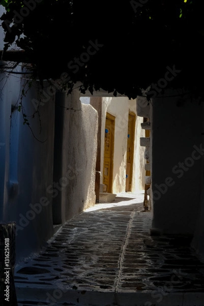 Obraz Narrow alley with tunnel and with whitewashed walls and stone pavement leading to a courtyard in the Greek Islands, Greece
