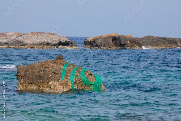 Obraz Fishing net abandoned on rock in the ocean polluting the seawater