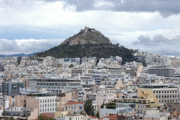 Fototapeta Athens cityscape expanding towards mountains under cloudy sky