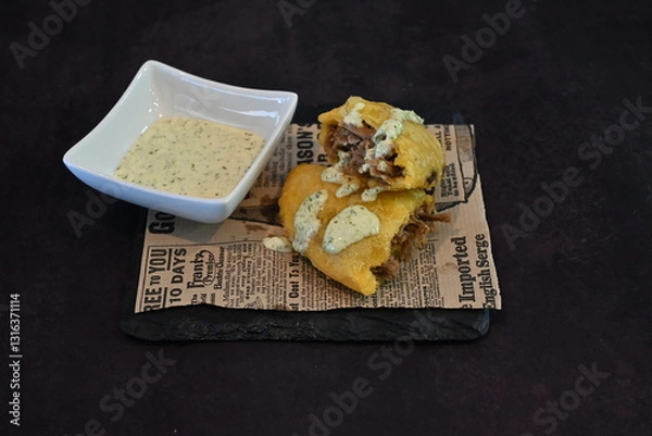 Obraz A plate of food with a dip and a newspaper on top