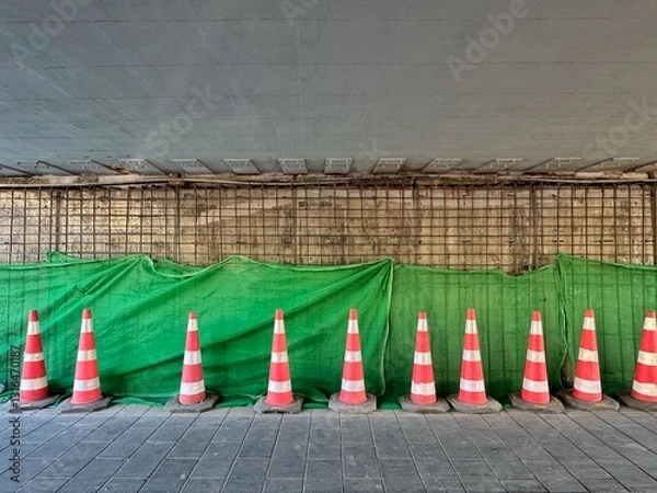 Obraz Construction is underway for the reconstruction of the tunnel under the road, on which work is being carried out. Orange traffic cones and tarp over construction wall