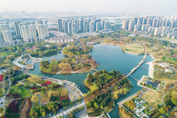 Obraz Aerial view of a lush urban park featuring water bodies and pathways amidst modern cityscape