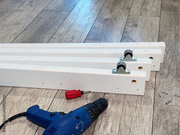 Fototapeta Wooden panels with wheels. Screwdriver nearby. Assembling an ottoman.