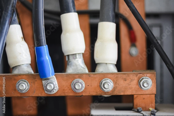 Fototapeta electrical connection.a black electrical wire with a white and blue sheath at the end is connected to a copper busbar, which is an important electrical conductor in the power distribution system.