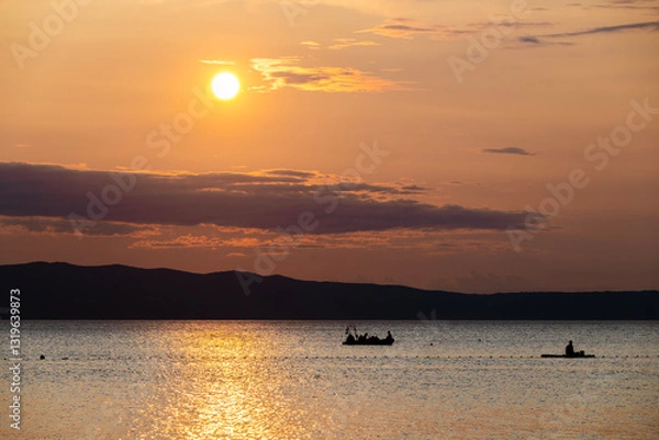 Fototapeta Dinghy passing in front of Cres island, Croatia with istrian peninsula rising in the background during wonderful, golden hour