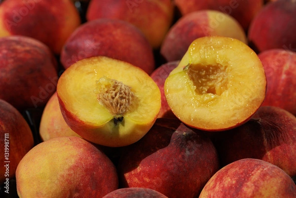 Fototapeta A close-up of fresh peaches, one cut in half, with the juicy, bright flesh inside