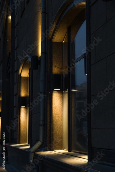Fototapeta Illumination of the granite-marble facade of the old building late at night