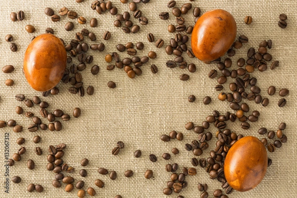 Obraz Coffee beans and Easter eggs, dyed with coffee on a background of burlap. Place for inscription