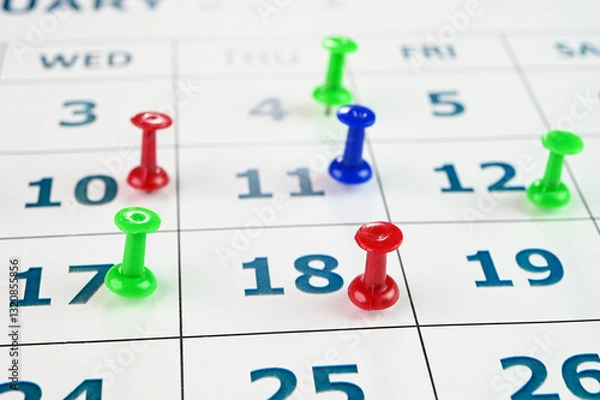 Obraz Multicolored thumbtacks on a monthly calendar.