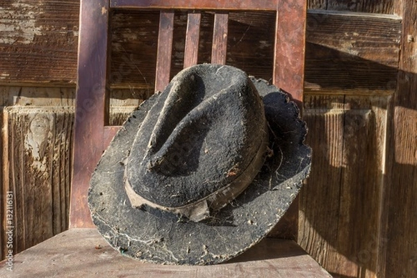 Obraz Battered old hat damaged by clothes moth on vintage background. A forgotten hat covered with spider web among the ruins of a house. Imagine the owner of this hat and tell their story.