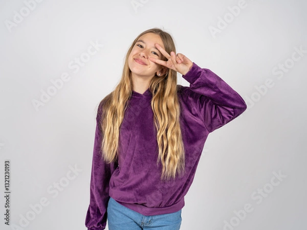 Fototapeta beautiful teen girl wearing purple sweater Doing peace symbol with fingers over face, smiling cheerful showing victory