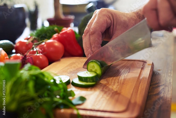 Fototapeta The procedure of slicing cucumber on a cutting board