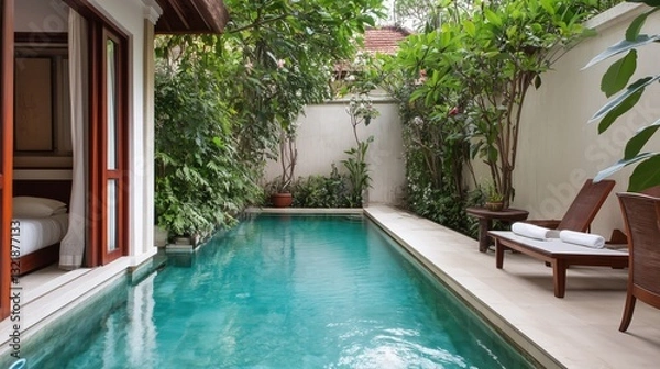 Fototapeta A pool with a wooden deck and a patio area with a bench and a chair. The pool is surrounded by trees and plants, creating a serene and relaxing atmosphere