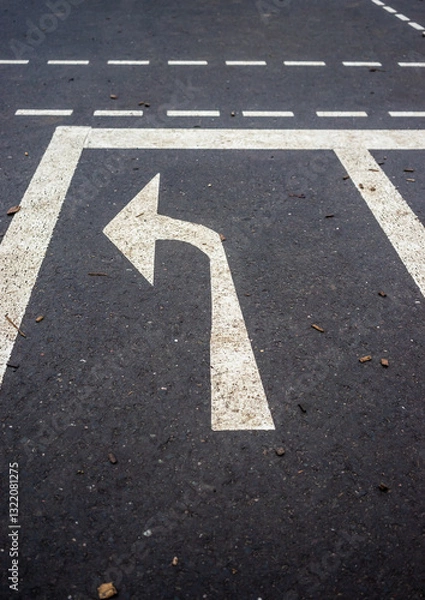 Fototapeta A white arrow pointing to the left is on a black road