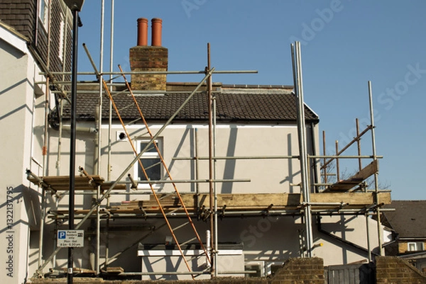 Fototapeta Construction or renovation of a house, exterior facade against the backdrop of a clear blue sky