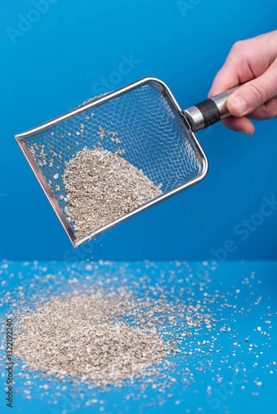 Obraz Clumping Cat Litter Scoop on Blue Background. Feline Care Routine: cleaning a cat kitty litter box and adding new absorber granules.