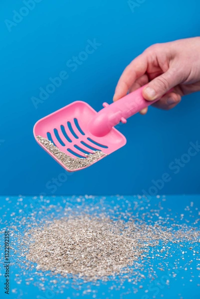 Obraz Clumping Cat Litter Scoop on Blue Background. Feline Care Routine: cleaning a cat kitty litter box and adding new absorber granules.