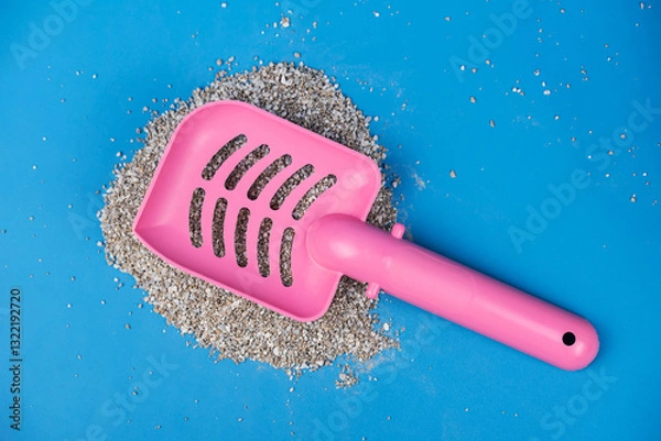 Obraz Clumping Cat Litter Scoop on Blue Background. Feline Care Routine: cleaning a cat kitty litter box and adding new absorber granules.
