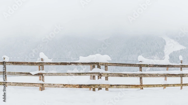 Fototapeta Snow-covered wooden fence on a mountain pasture. Winter landscape on a mountain hiking trail on a cloudy and foggy day.