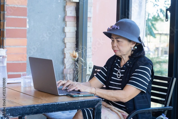 Fototapeta Lifestyle elderly female after retirement checking stock investment performance in digital tecnology laptop at cafe talk to friends using smartphone, healthy lifestyle pensioner drink wine on holiday