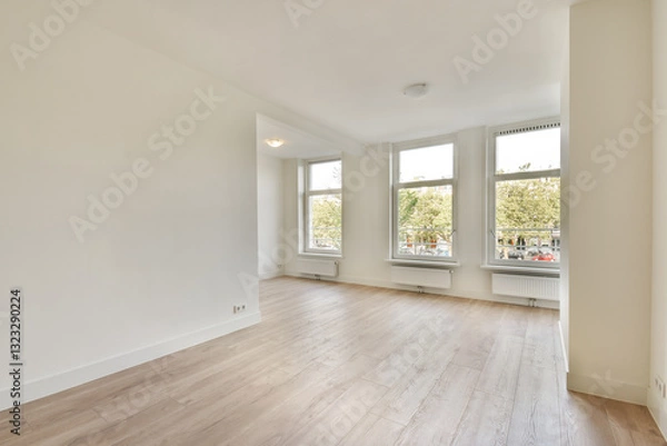 Fototapeta An inviting empty room featuring large windows that flood the space with natural light, showcasing clean lines and a fresh feel.